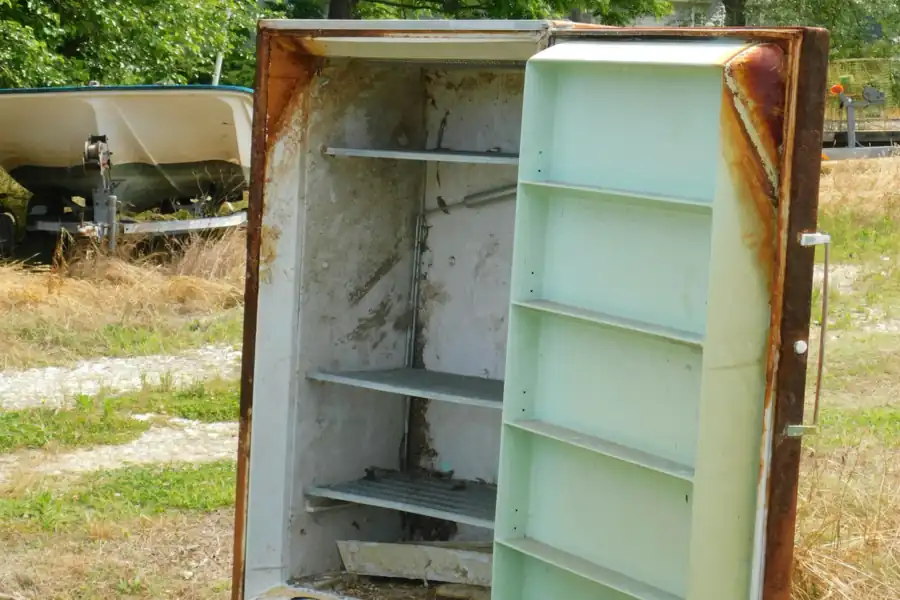 A rusted-out old refrigerator sitting outside, waiting to be hauled off